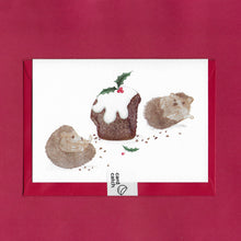 Load image into Gallery viewer, A hand drawn illustration on a greeting card of two hedgehogs lounging around surrounded by crumbs after eating too much Christmas pudding. The card is on top of festive red envelope and held together by a 100% plastic free card catch sticker
