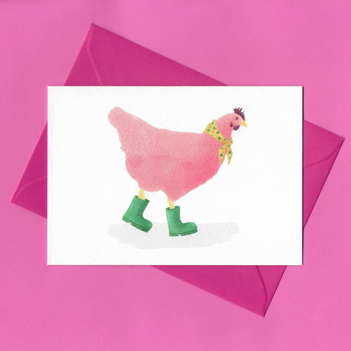 A stylised watercolour illustration of a pink chicken, wearing a yellow scarf with green flowers around its neck, and green wellies on its feet, on a greeting card. With a bright pink envelope on a pink background.