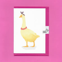 Load image into Gallery viewer, A stylised watercolour illustration of a yellow goose, wearing a purple headscarf and red beaded necklace, on a greeting card, with a bright pink envelope held together by an eco friendly plastic free card catch sticker, on a pink background
