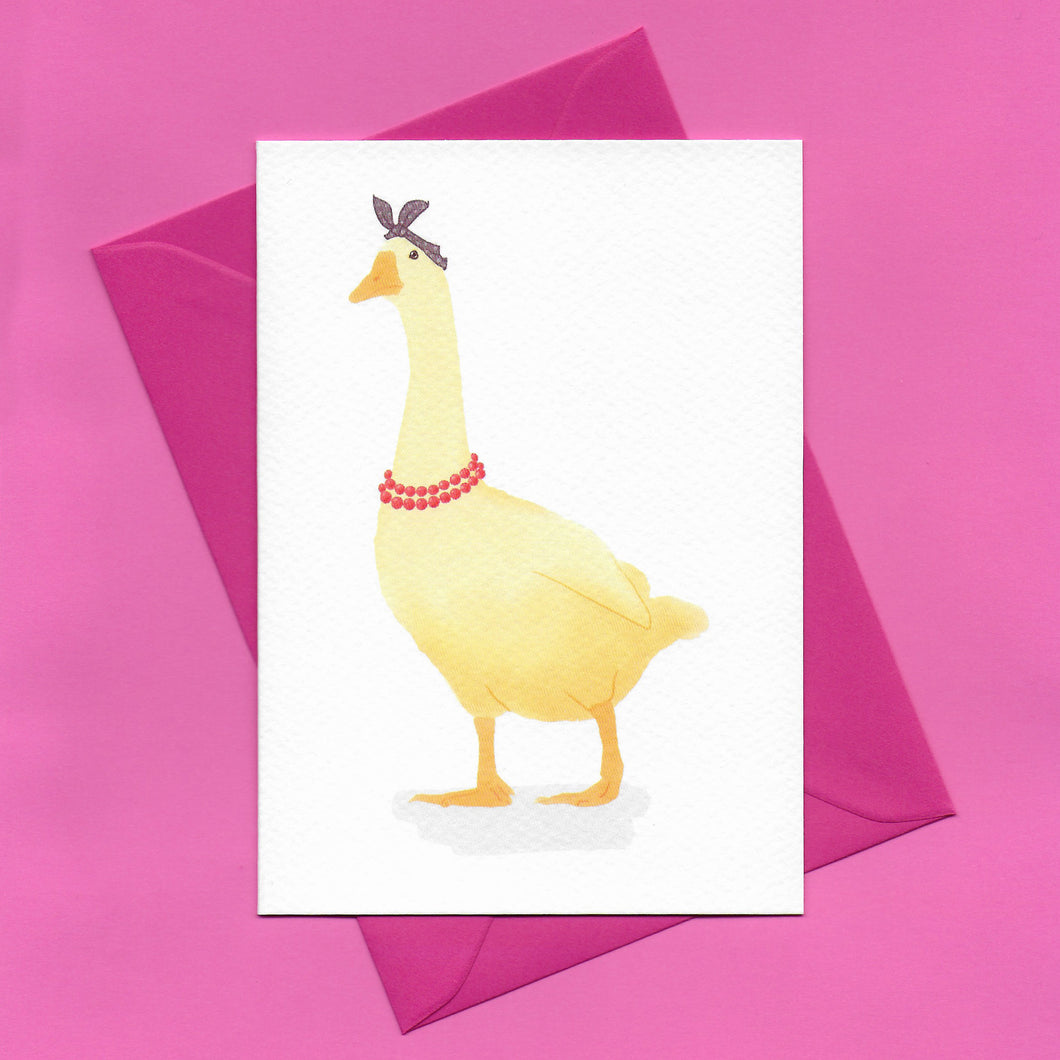 A stylised watercolour illustration of a yellow goose, wearing a purple headscarf and red beaded necklace, on a greeting card, with a bright pink envelope, on a pink background