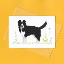 Load image into Gallery viewer, A stylised watercolour illustration on a luxury greeting card of a black and white collie dog amongst grass and wildflowers and a butterfly, with a bright yellow envelope, on a yellow background
