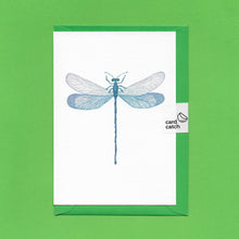 Load image into Gallery viewer, A detailed colour illustration on a luxury greeting card of a blue iridescent dragonfly, with a bright green envelope held together with an eco friendly plastic free card catch sticker, sitting on a green background
