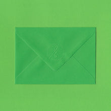 Load image into Gallery viewer, A bright green envelope with the Elizabeth May Designs logo embossed on the flap, sitting on a green background
