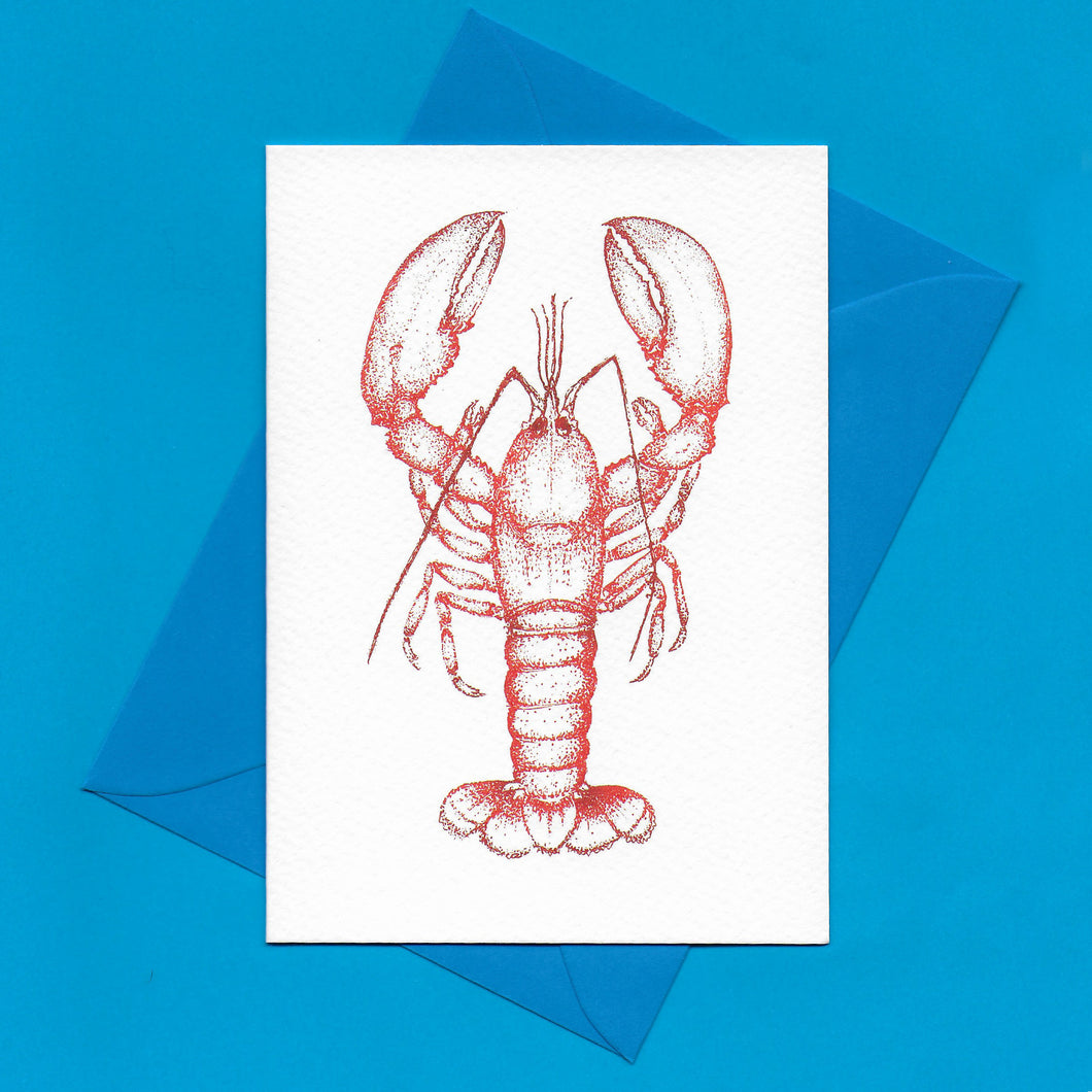 A detailed colour illustration on a luxury greeting card of a red coloured lobster, with a kingfisher blue envelope, sitting on a blue background